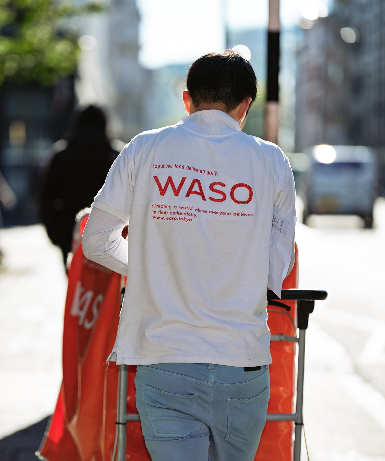 Photograph of a WASO delivery person pushing a cart on a city street