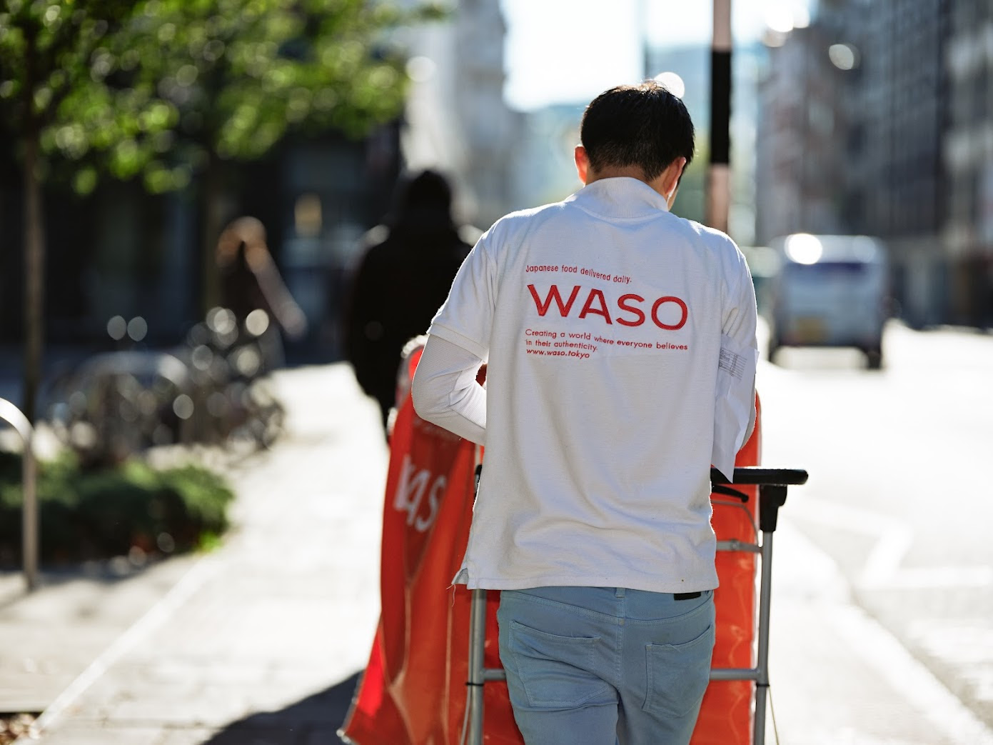 Delivery staff walking with a red trolley on a street